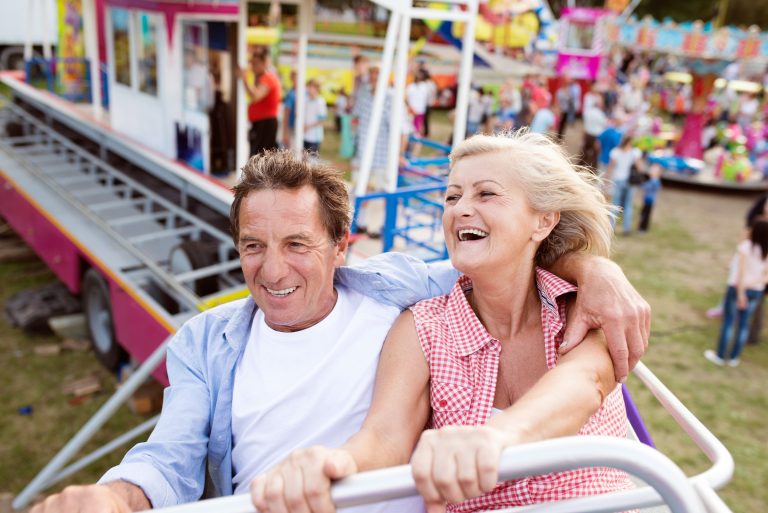 A senior couple that is taking a ride on a roller coaster together.